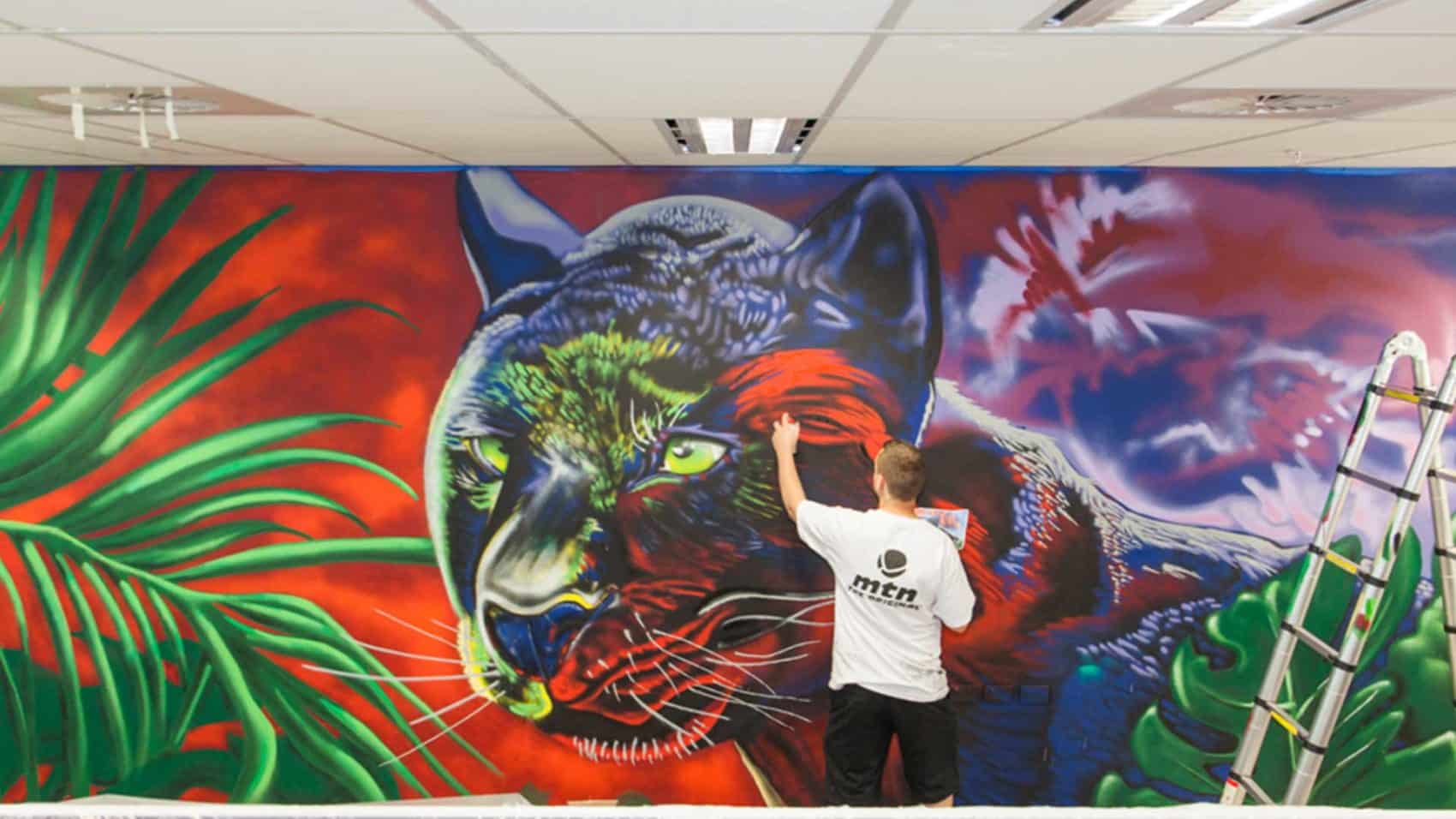 Colorful panther graffiti mural with lush green leaves in the background.