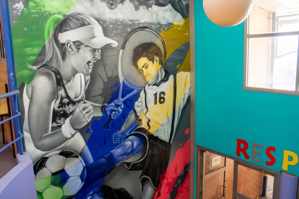 Colorful mural of students playing soccer and guitar at Ambarvale High School.