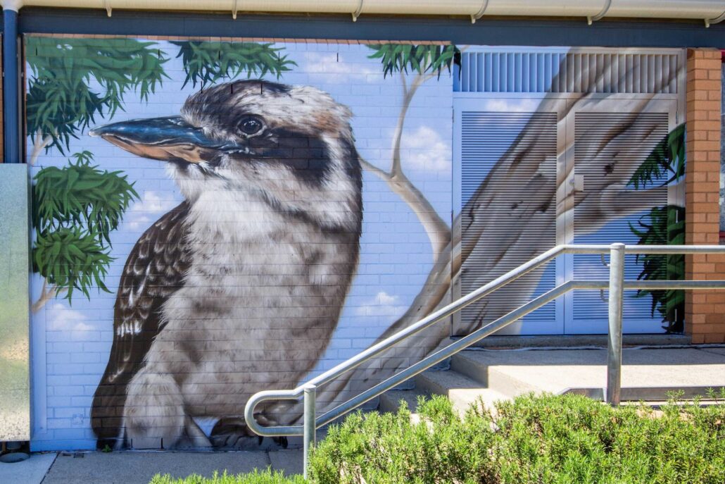 Vivid mural of a koala and bird on a building wall in Blackbook Ink style.