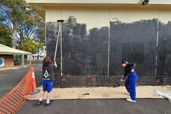 Primary school students helping paint mural