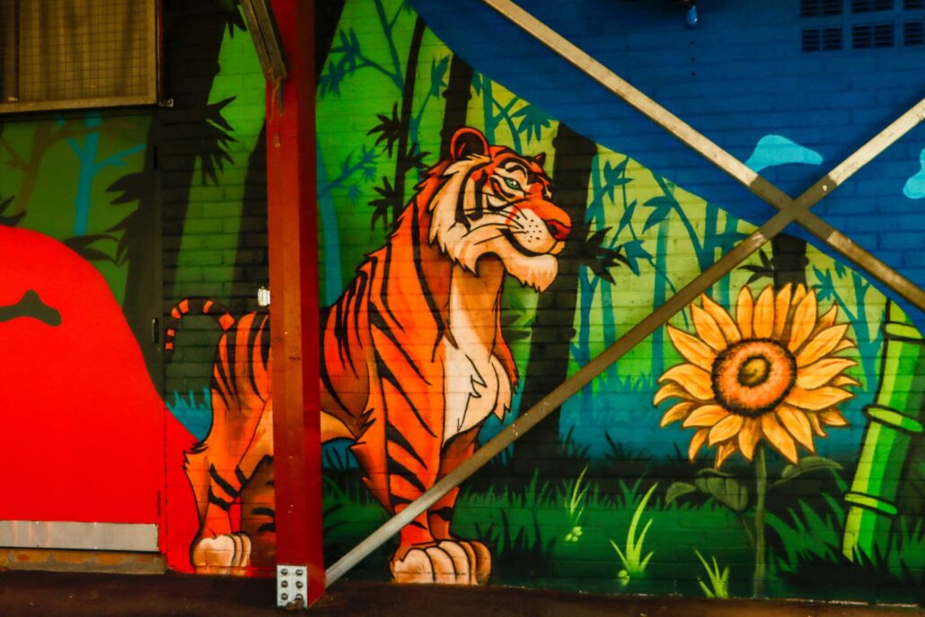 Colorful tiger and sunflower mural at Blackbook Ink tattoo studio in Australia.