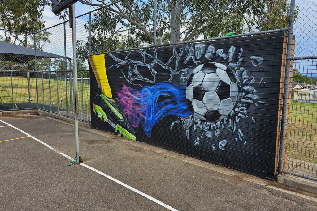 Madang-Ave-Mural-7 Kicking a ball at a wall mural at Sydney School
