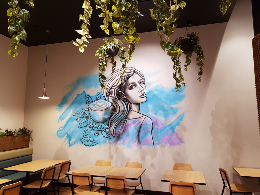 Vibrant mural of a woman with coffee and foliage in Perth cafe.